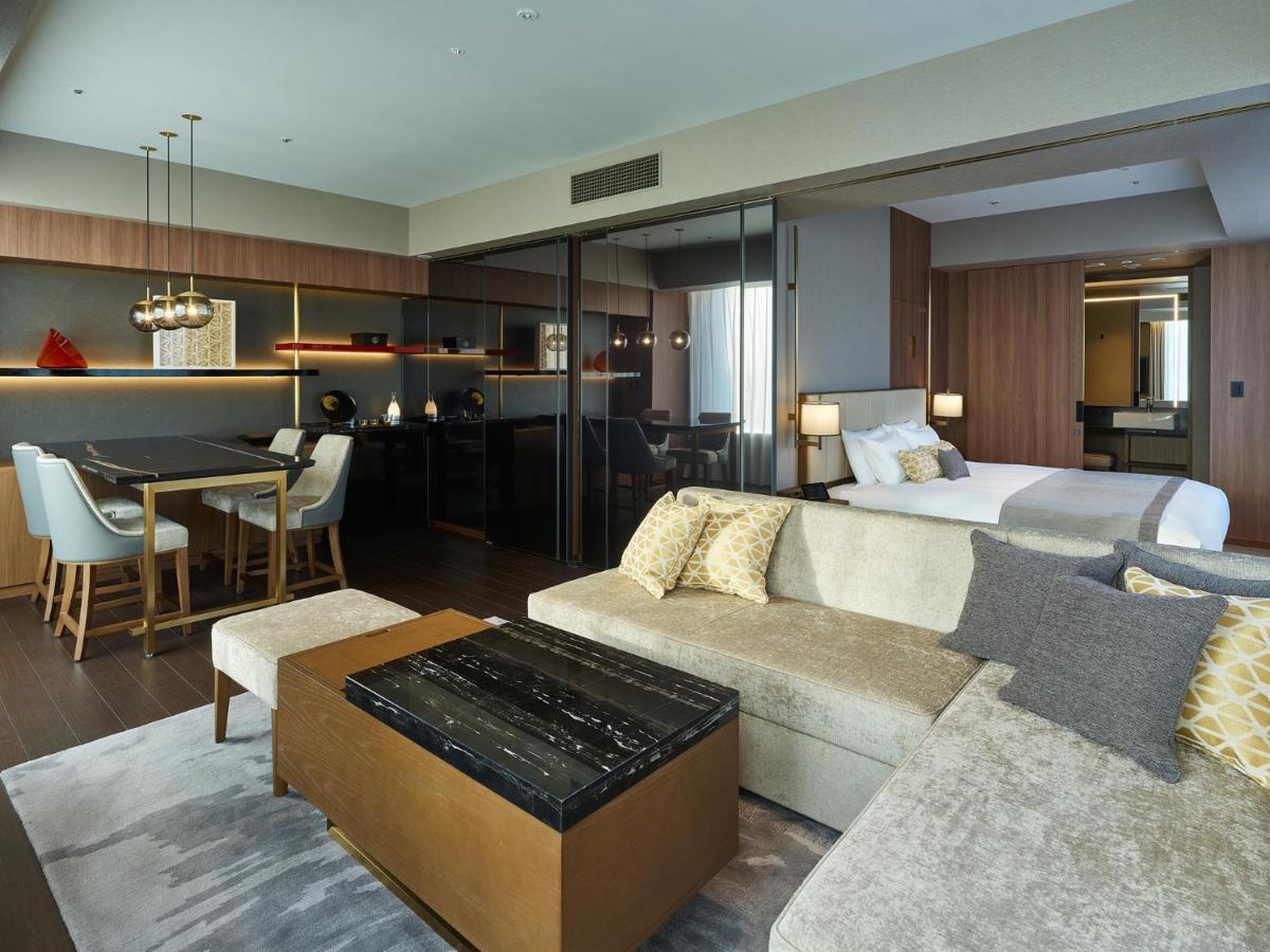 Mitsui Garden Hotel Roppongi Tokyo Premier Exteriör bild The image shows a modern hotel room or suite that features a contemporary design. Key elements include:

- A comfortable seating area with a light-colored sofa and a stylish coffee table.
- A dining area with a table and chairs, suggesting space for 