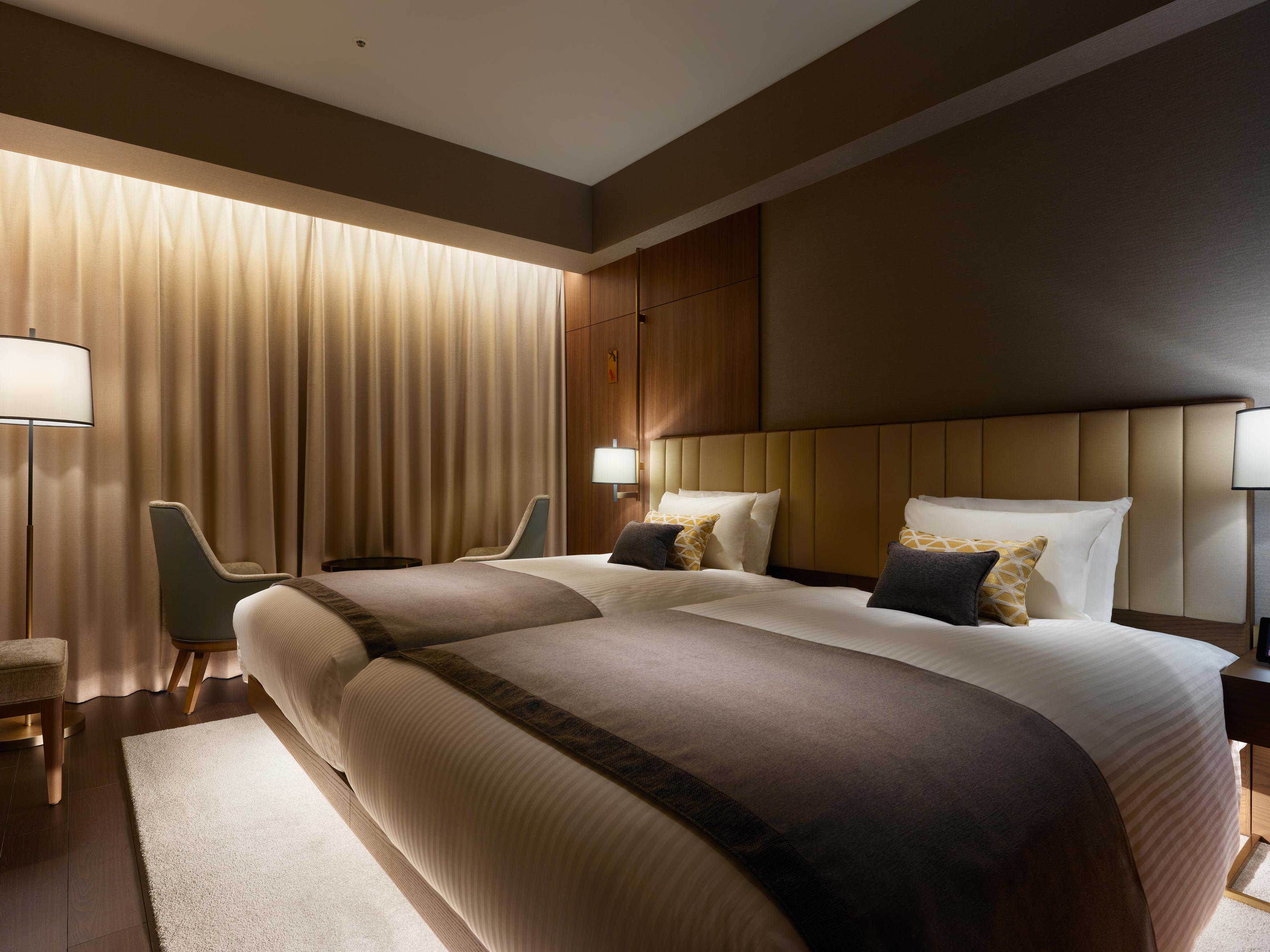 Mitsui Garden Hotel Roppongi Tokyo Premier Exteriör bild The photo shows a modern hotel room featuring two twin beds with elegant bedding. The room is adorned with soft, neutral tones and has a warm ambiance created by subtle lighting. A pair of bedside lamps provide additional light, and there is a cozy c
