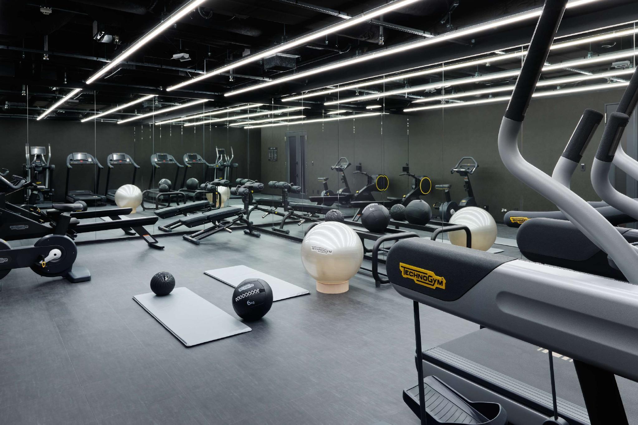 Mitsui Garden Hotel Roppongi Tokyo Premier Exteriör bild The photo shows a modern gym interior. The space features various exercise equipment, including cardio machines like treadmills and elliptical trainers, weight machines, and free weights. There are also exercise mats and fitness balls scattered throu